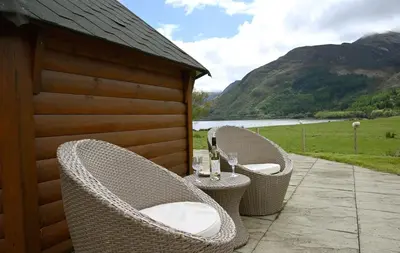 two wicker chairs sitting on a patio next to a building at Leven View Lodges - Carness in Fort William