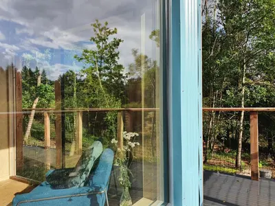 a blue chair sitting on a porch looking out a window at Mertrick in Forest Mill