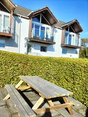 a wooden picnic table in front of a building at Seaview cosy 2 bed home in Lamlash - 'Mid Drive' in Lamlash