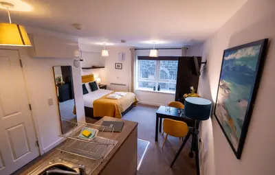 a hotel room with a bedroom with a bed and a mirror at Talisker Apartrment in Oban