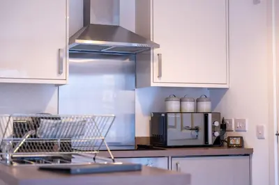 a kitchen with white cabinets and a counter with a microwave at Talisker Apartrment in Oban