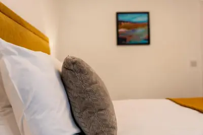 a pillow on a bed with a picture on the wall at Lagavulin Apartment in Oban