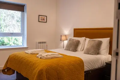 a bedroom with a bed with a yellow blanket at Lagavulin Apartment in Oban