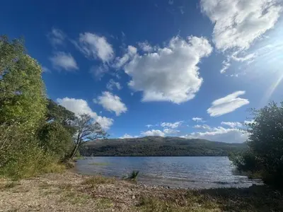 a large body of water with a blue sky and clouds at Bell Rock Holiday Lodge in Killin