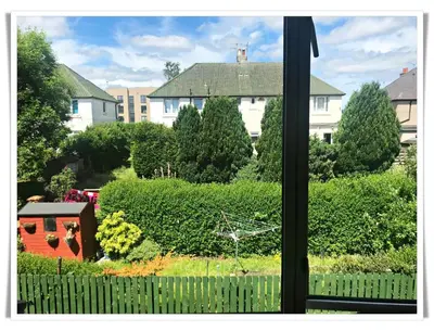 a window with a view of a yard with houses at Bright & Spacious Double Room with Garden View- Close to Airport & City Centre in Edinburgh
