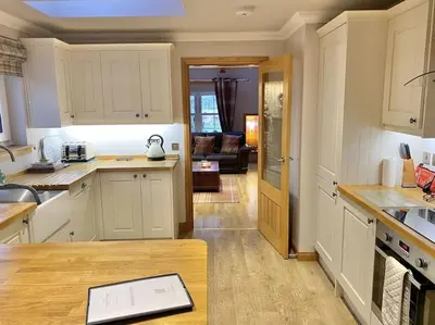a kitchen with white cabinets and a table in it at The Old Schoolhouse Lochearnhead in Lochearnhead