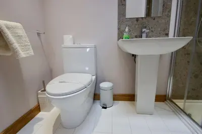 a white bathroom with a toilet and a sink at The Old Schoolhouse Lochearnhead in Lochearnhead
