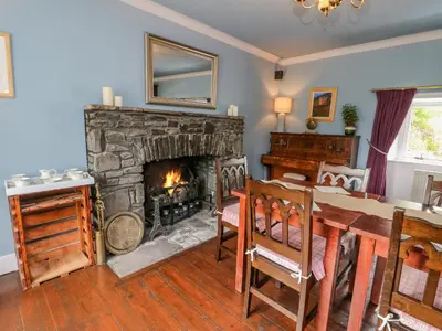 a living room with a fireplace and a dining room table at The House at Bridge of Lochay in Killin