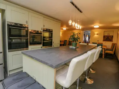 a kitchen with a large island with white cabinets at The House at Bridge of Lochay in Killin