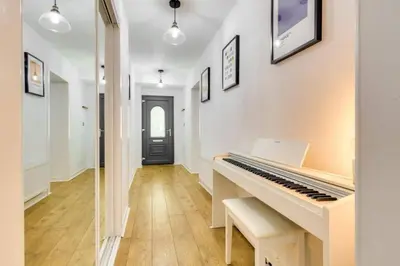 a white piano in a hallway with a door at Lovely 2 Bedroom Garden Flat in trendy West End in Glasgow