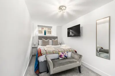 a bedroom with a bed with a chair and a mirror at RÌGH Properties - Luxury West End Artisan Apartment in Edinburgh