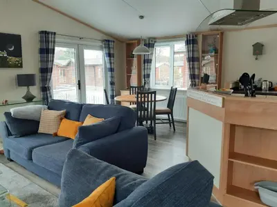 a living room with a blue couch and a kitchen at Sycamore Lodge Auchterarder in Auchterarder