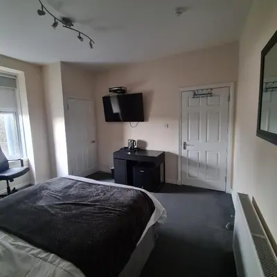 a bedroom with a bed and a tv on the wall at The Beath Inn in Cowdenbeath