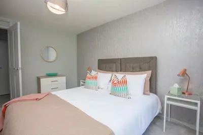 a bedroom with a white bed with colorful pillows at Beautiful West End Flat with Private Parking in Glasgow
