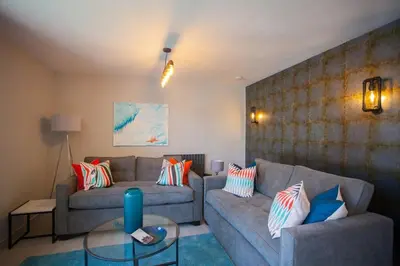 a living room with a gray couch with colorful pillows at Beautiful West End Flat with Private Parking in Glasgow