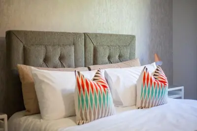 a bed with white pillows with colorful striped pillows at Beautiful West End Flat with Private Parking in Glasgow