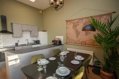 a dining room with a table and chairs and a kitchen at Glasgow Green Getaway with Free Parking in Glasgow