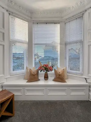 a white room with a bench with flowers and windows at No.3 The Villa in Oban