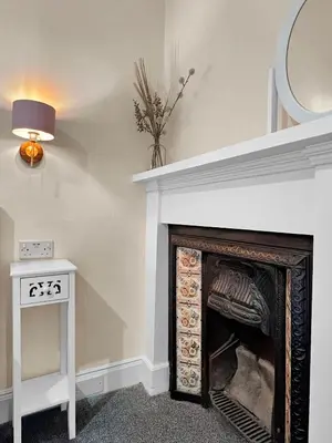 a fireplace in a room with a table and a lamp at No.3 The Villa in Oban