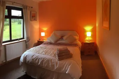a bedroom with a bed with two lamps and a window at Snowberry Cottage No 2 in Onich