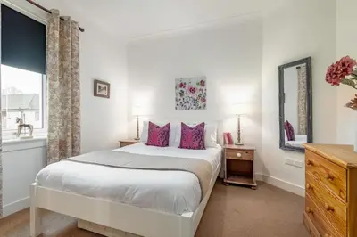 a bedroom with a large white bed with pink pillows at Heather Cottage, 2 bedroom in Comrie in Comrie