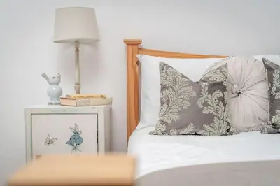 a bed with pillows and a table with a lamp at Heather Cottage, 2 bedroom in Comrie in Comrie