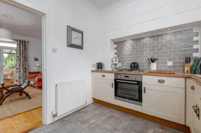 a kitchen with white cabinets and a brick wall at Heather Cottage, 2 bedroom in Comrie in Comrie
