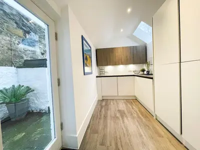 a kitchen with white cabinets and a large window at 2Bed, Private Garden & Fireplace, Near Water of Leith in Edinburgh