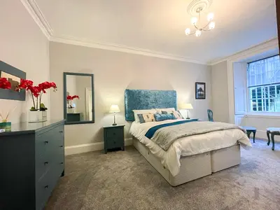 a bedroom with a bed and a dresser and a mirror at 2Bed, Private Garden & Fireplace, Near Water of Leith in Edinburgh