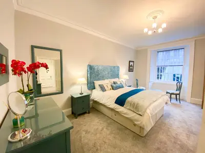 a bedroom with a bed and a table and a mirror at 2Bed, Private Garden & Fireplace, Near Water of Leith in Edinburgh