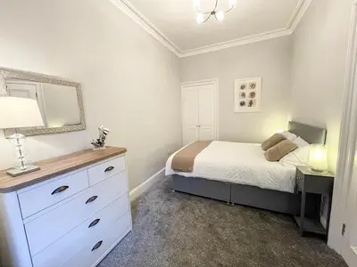 a bedroom with a bed and a dresser with a mirror at 2Bed, Private Garden & Fireplace, Near Water of Leith in Edinburgh
