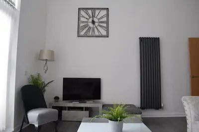 a living room with a radiator and a tv at THE PAISLEY PENTHOUSE - ABBEY VIEW in Paisley