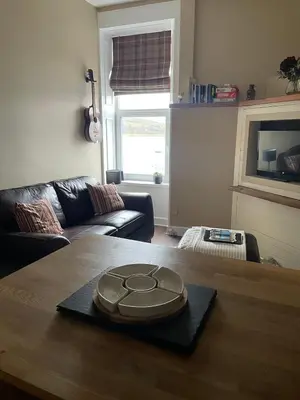 a living room with a wooden table and a couch at An Cuilidh in Port Bannatyne
