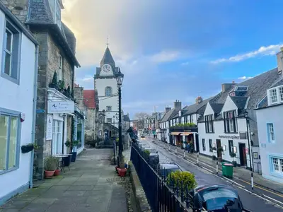 a street with a clock tower in a town at Stunning Loft Apartment South Queensferry High St Bridge Views! in Queensferry
