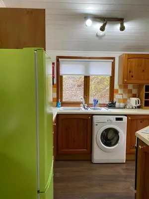 a kitchen with a refrigerator and a washing machine at Walled Garden Lodges Loch Lomond in Balloch