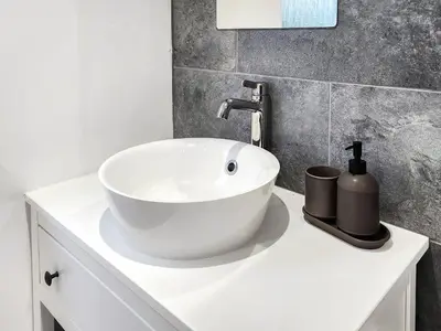 a bathroom with a white sink and a gray wall at Riverside Cottage in Larkhall