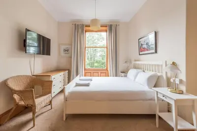a bedroom with a bed and a desk and a window at Beautiful 2 Bed 2 Bath Flat overlooking Meadows Park in Edinburgh