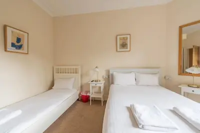 two white beds in a room with a mirror at Beautiful 2 Bed 2 Bath Flat overlooking Meadows Park in Edinburgh