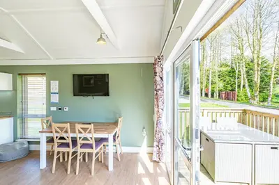 a dining room with a table and a balcony at Squirrel Lodge 40 with Hot Tub in Newton Stewart