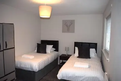 a bedroom with two beds and a lamp at Kelpies Serviced Apartments- Cromwell Apt in Falkirk