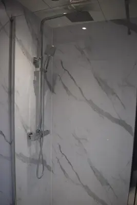 a bathroom with a shower with white marble walls at Kelpies Serviced Apartments- Cromwell Apt in Falkirk