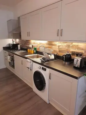 a kitchen with a sink and a washing machine at Modern flat near city centre. in Edinburgh