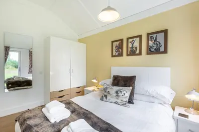 a bedroom with a white bed with towels on it at Squirrel Lodge 43 with Hot Tub in Newton Stewart