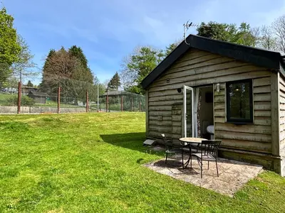 a small shed with a table and chairs in a yard at Squirrel Lodge 43 with Hot Tub in Newton Stewart