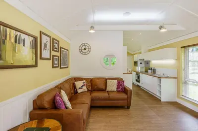 a living room with a brown couch and a kitchen at Squirrel Lodge 43 with Hot Tub in Newton Stewart