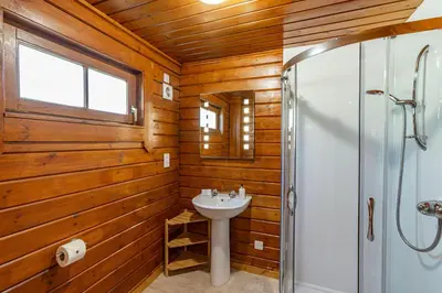 a bathroom with wooden walls and a sink and a shower at Lady Galloway 27 with Hot Tub in Newton Stewart