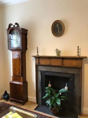 a living room with a grandfather clock and a fireplace at charm & character on historic Rose Street in Edinburgh