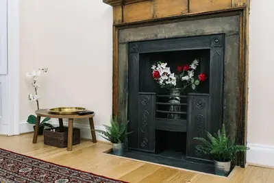 a fireplace with a vase of flowers in a room at charm & character on historic Rose Street in Edinburgh
