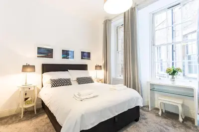 a white bedroom with a large bed and two windows at GLASGOW WEST END 5 MIN WALK TO SECC AND HYDRO in Glasgow