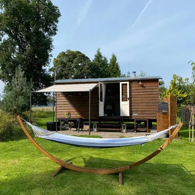 a hammock in front of a tiny house at Poachers Hut at Keepers Cottage - Hot Tub & Pizza Oven - Trossachs in Port of Menteith